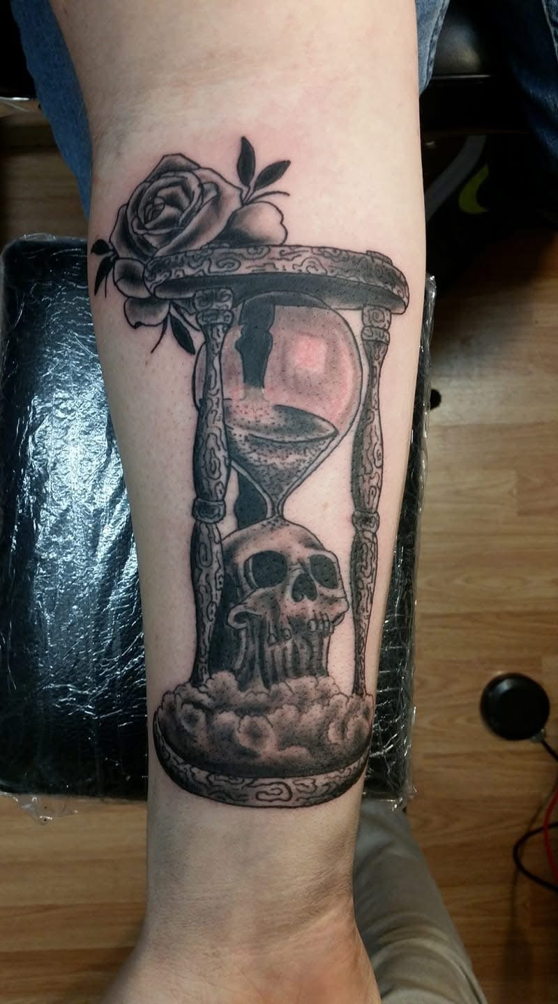 Hourglass with skull at base and rose on top forearm tattoo