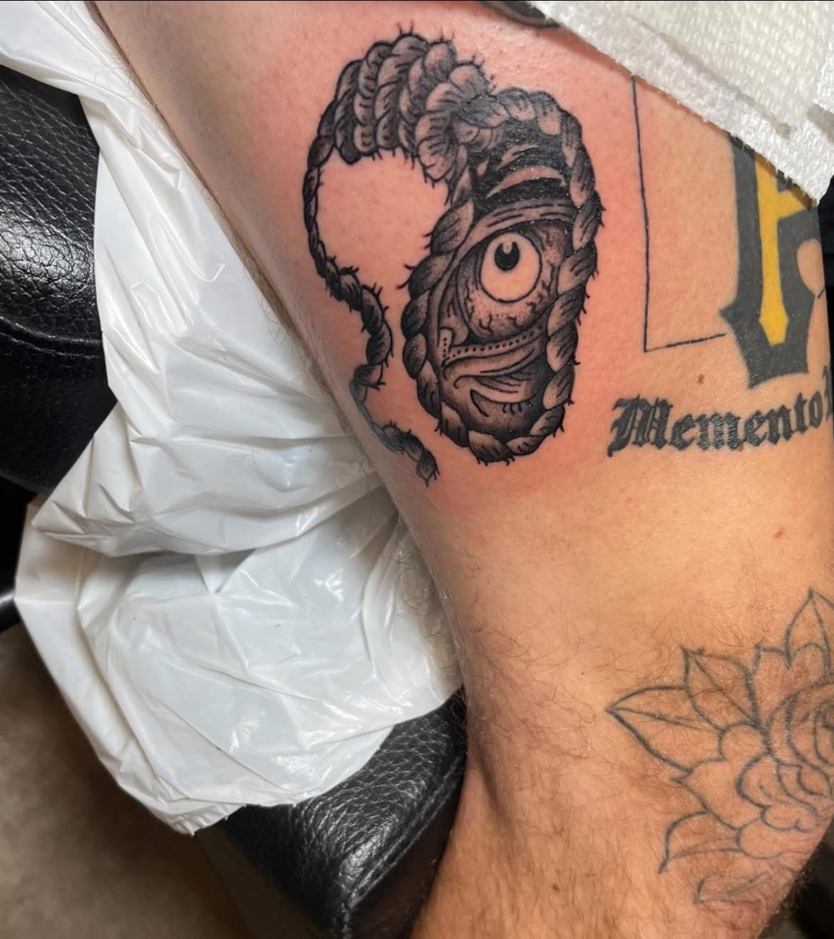 Cyclops creature with braided rope frame arm tattoo