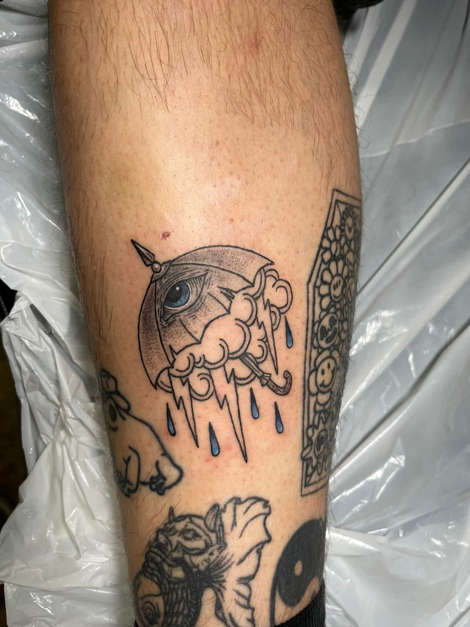 All seeing eye with storm cloud lightning and blue rain drops arm tattoo