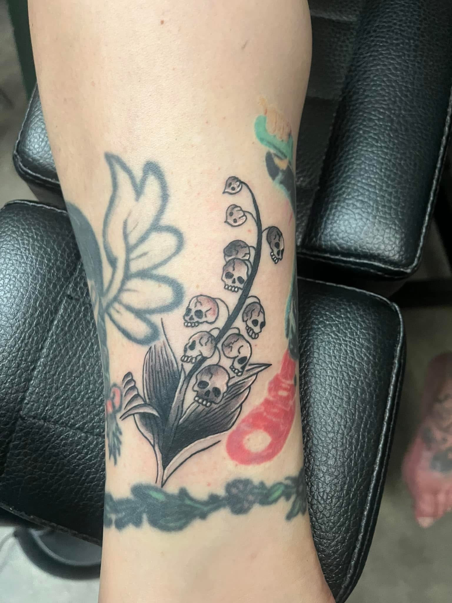 Lily of the valley with skulls instead of flowers arm tattoo