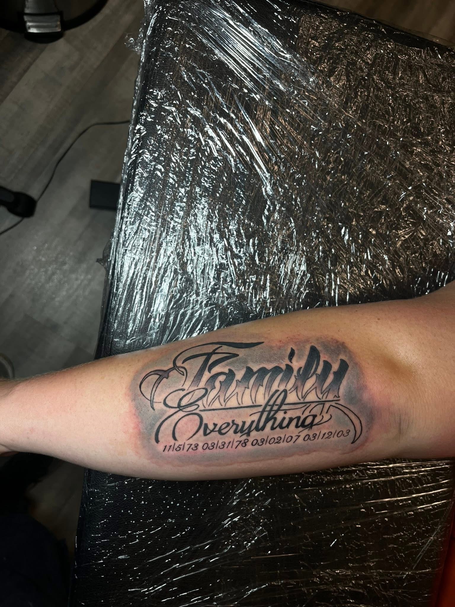 Family Everything script with memorial dates forearm tattoo