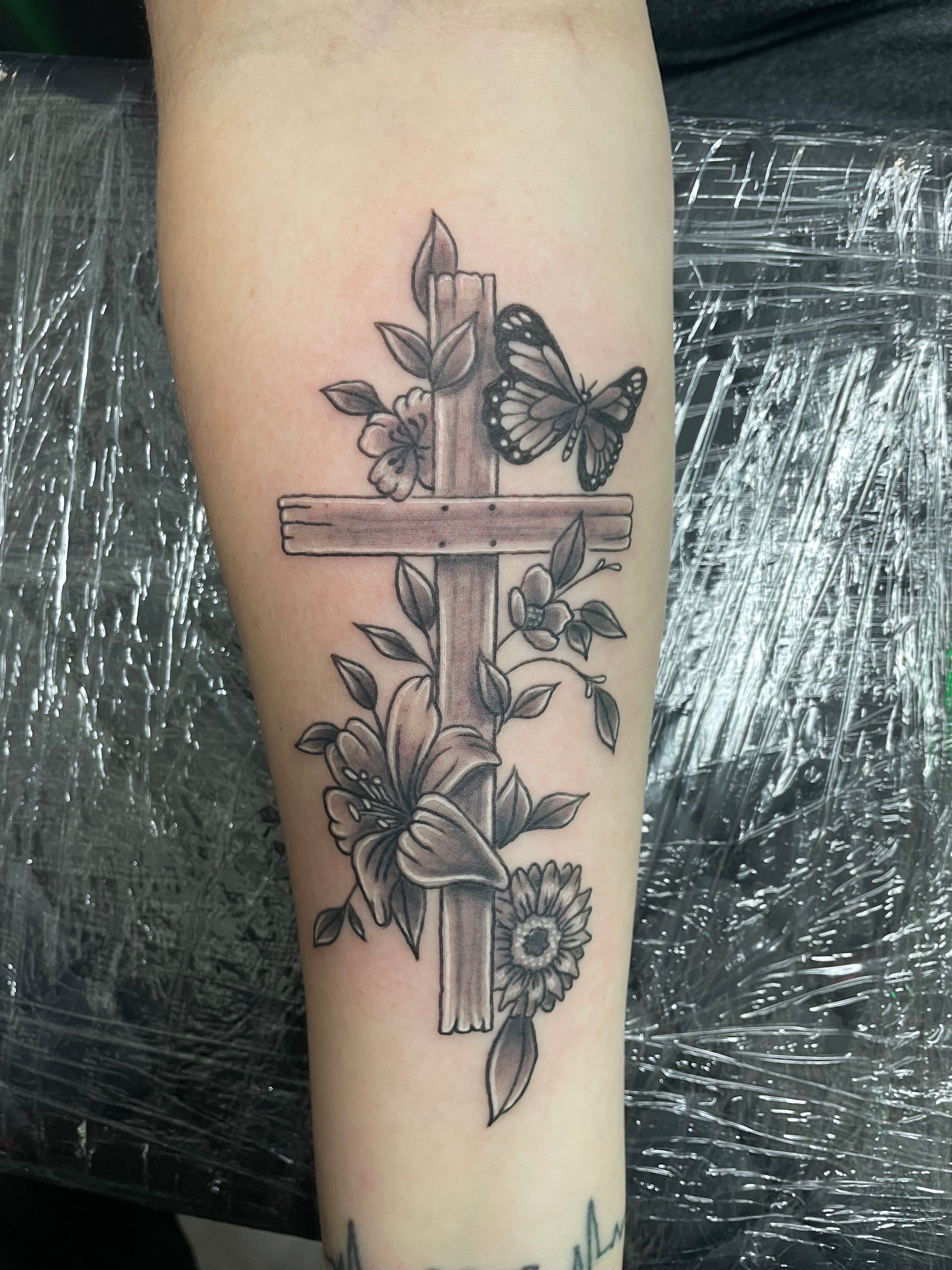 Randy DeShong wooden cross butterfly and flowers forearm tattoo